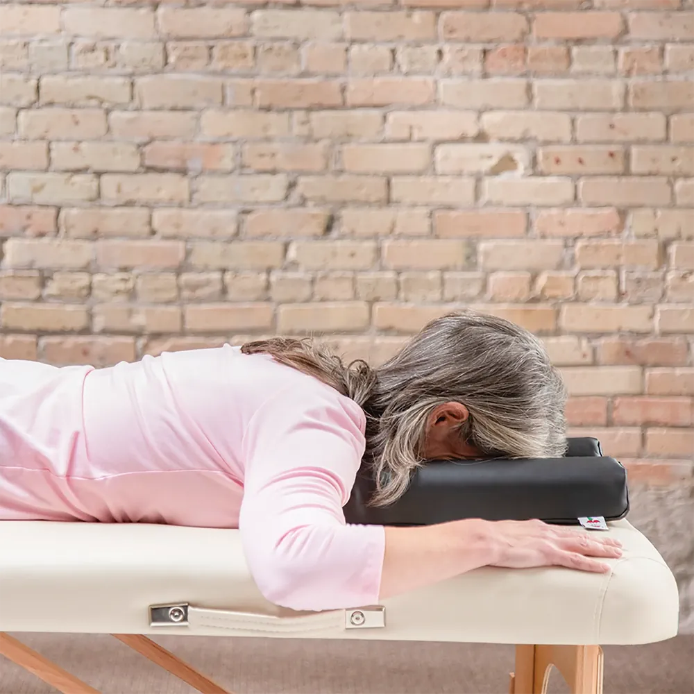 Client laying prone face-down on the Max Relax face rest on top of a massage table.